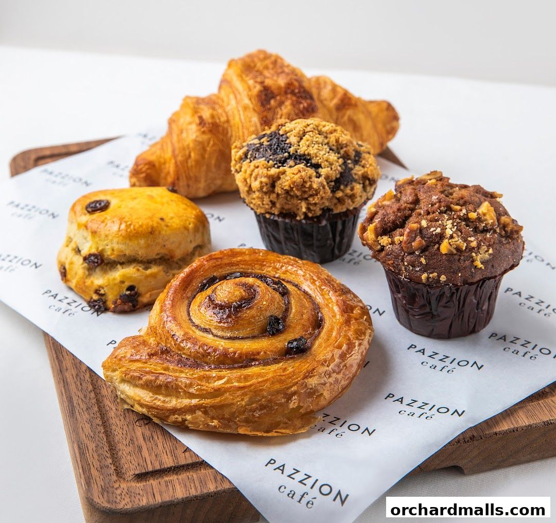 A selection of freshly baked pastries including a croissant, muffins, a scone, and a cinnamon roll.