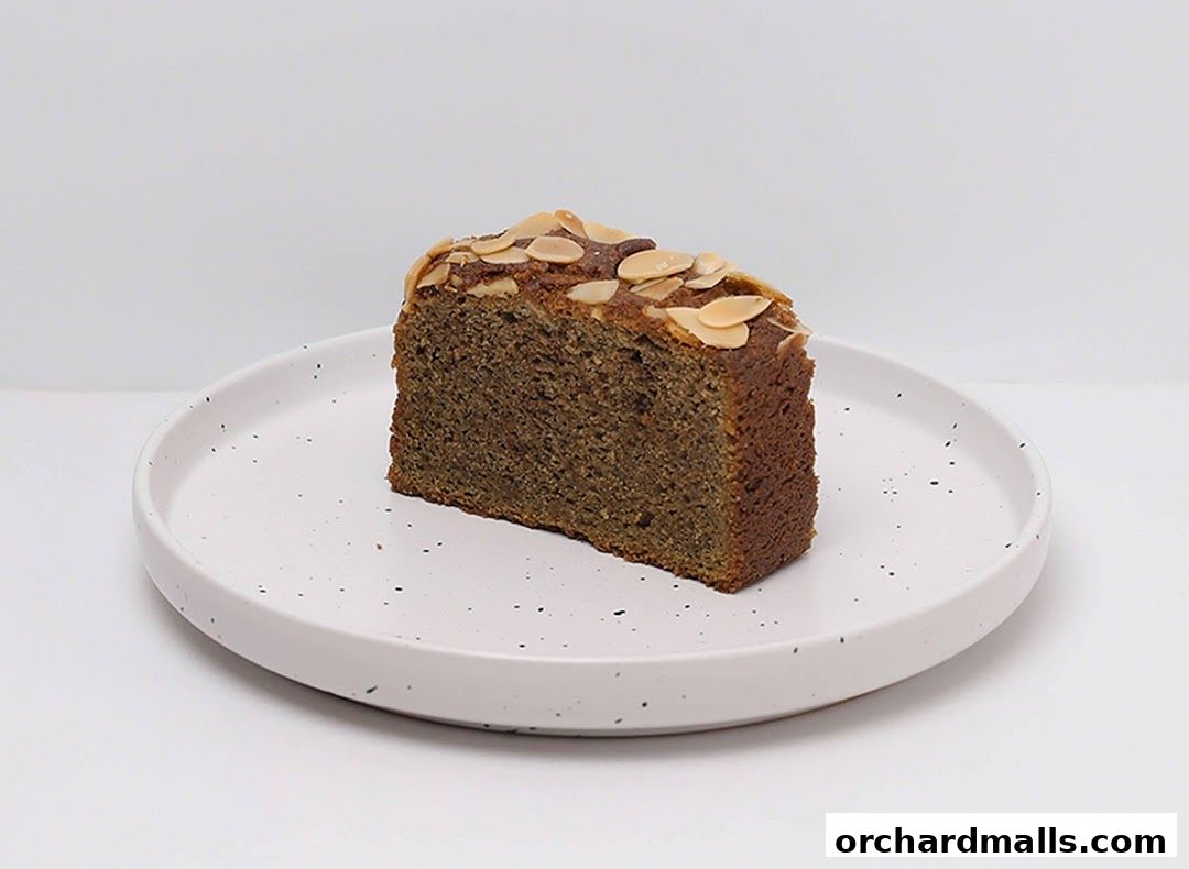 A slice of almond cake on a speckled white plate against a white background.