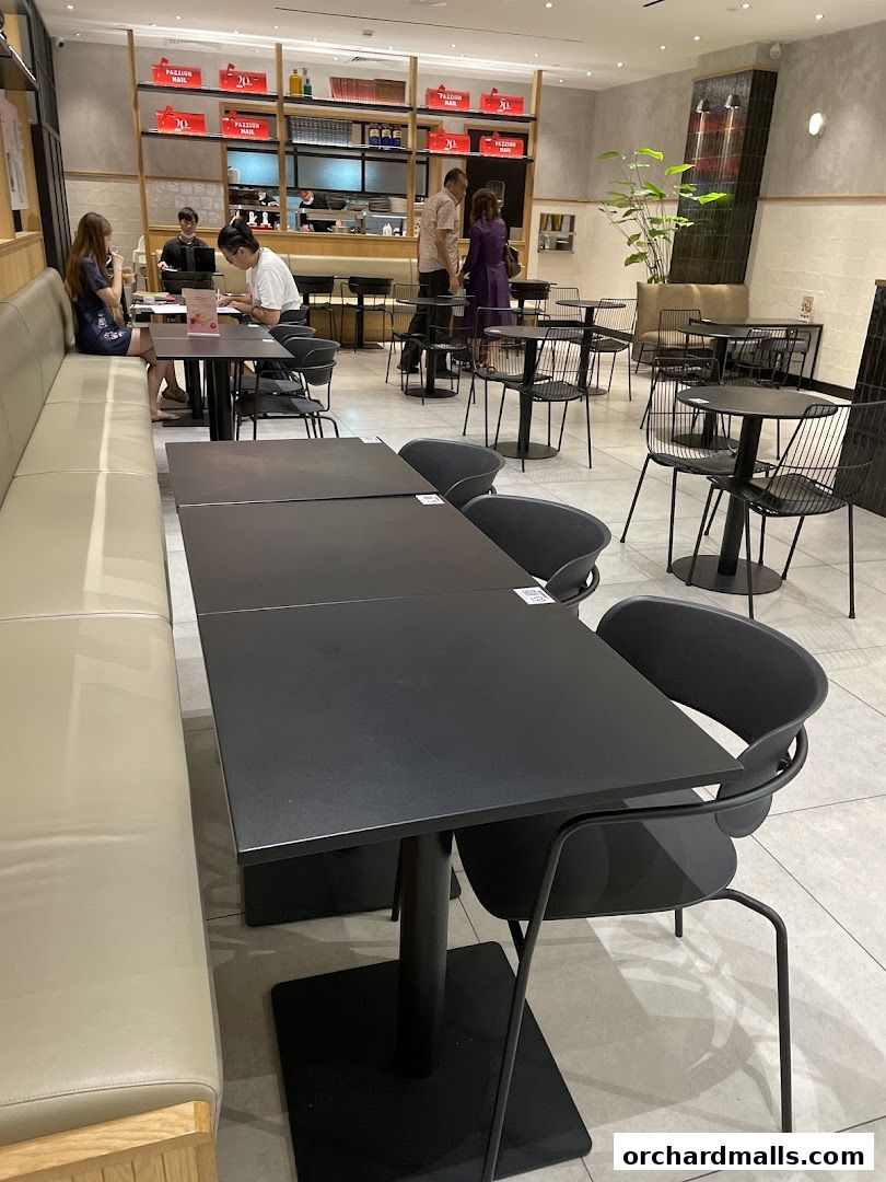 Interior view of PAZZION Takashimaya Shopping Centre with tables, chairs, and customers.