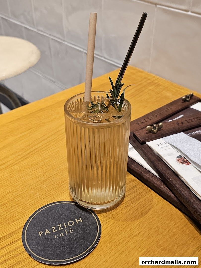 A refreshing drink with rosemary garnish on a table at PAZZION cafe.