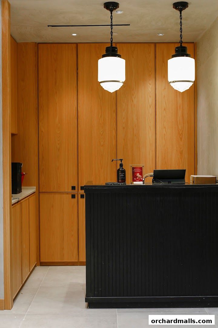 A modern reception area with wooden cabinets, a black counter, and stylish pendant lights.