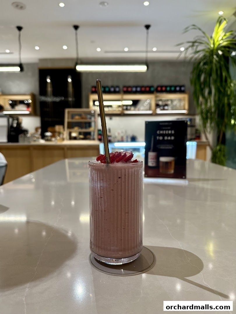 A refreshing strawberry smoothie served in a fluted glass with a metal straw.