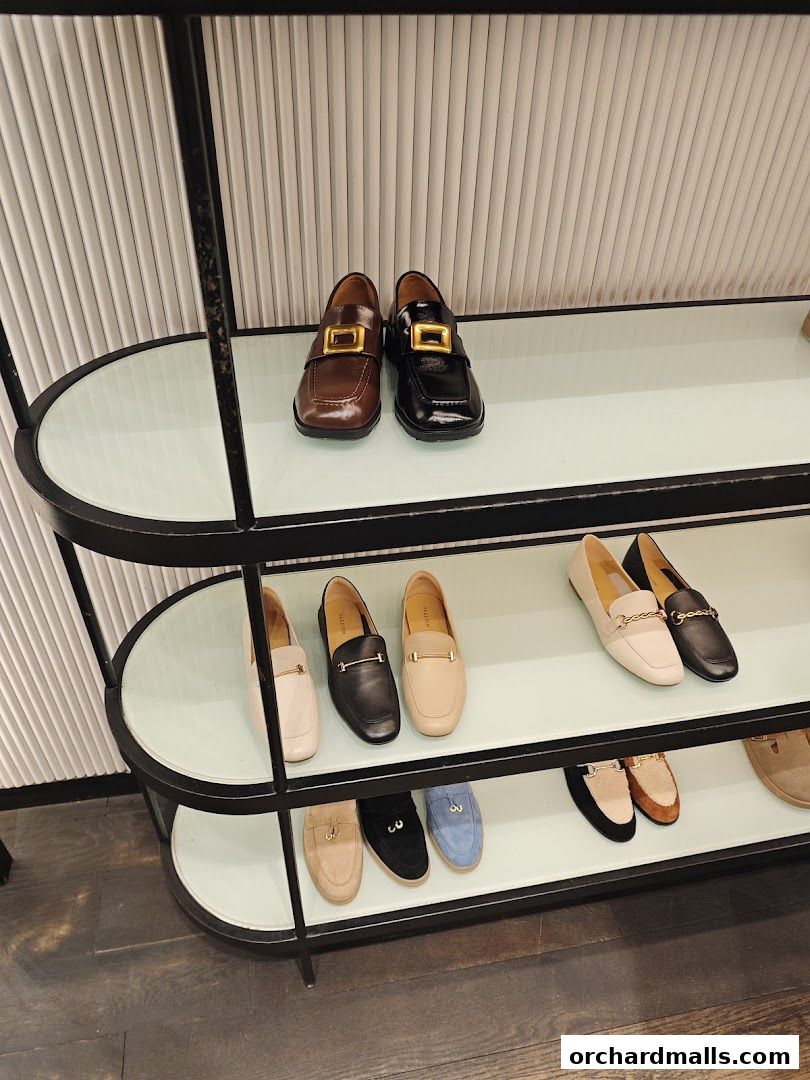 A display of various loafers and flats on shelves in a shoe store.