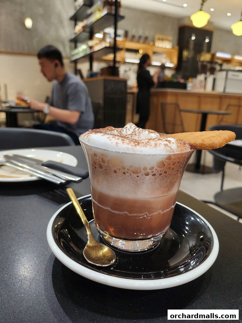 A close-up of a decadent hot chocolate topped with whipped cream and a biscuit.