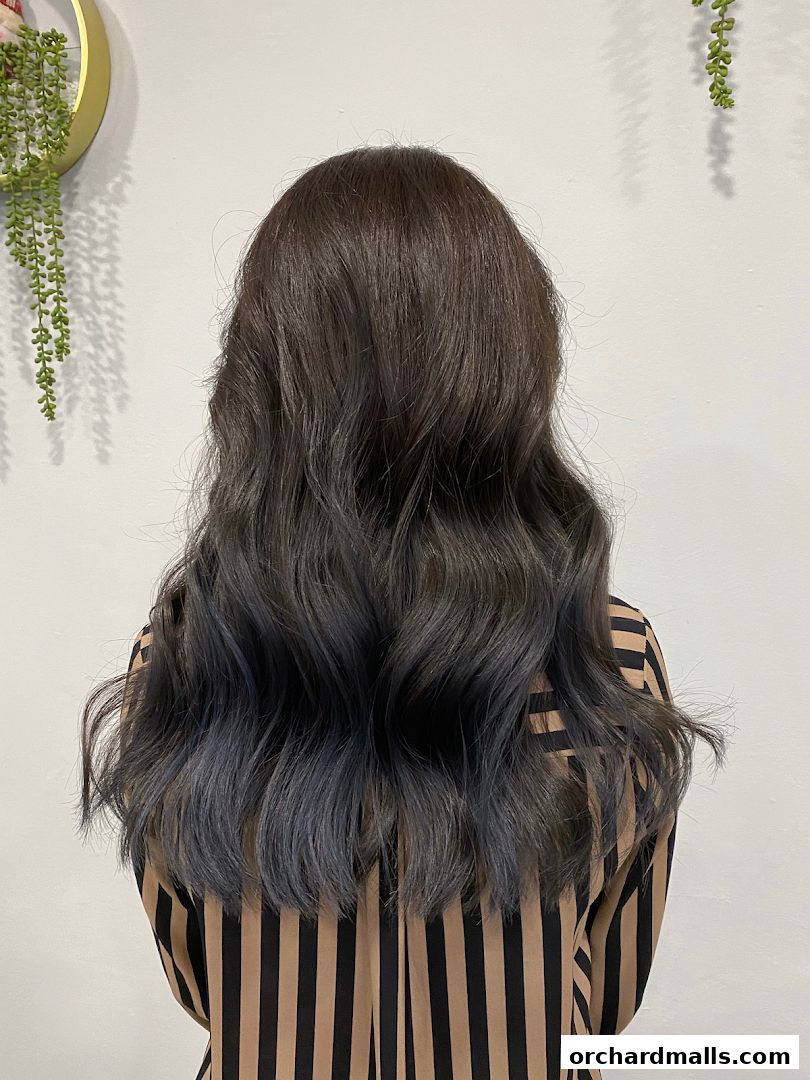 A person with long, wavy, dark hair with blue-grey ombre ends.