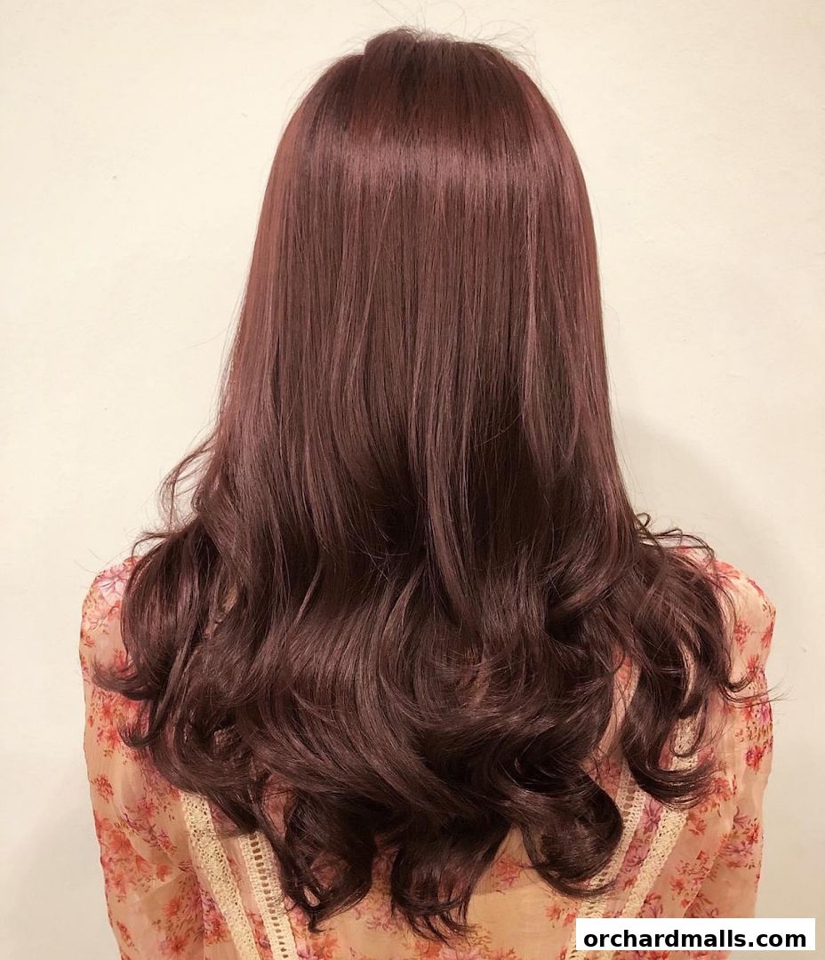 A person's back with long, wavy, dark auburn hair styled elegantly.