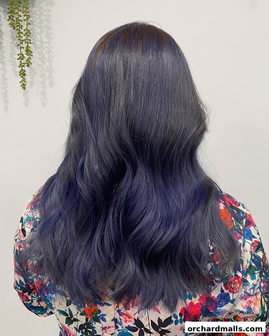 A person's back with long, wavy, dark blue-grey hair and a floral shirt.