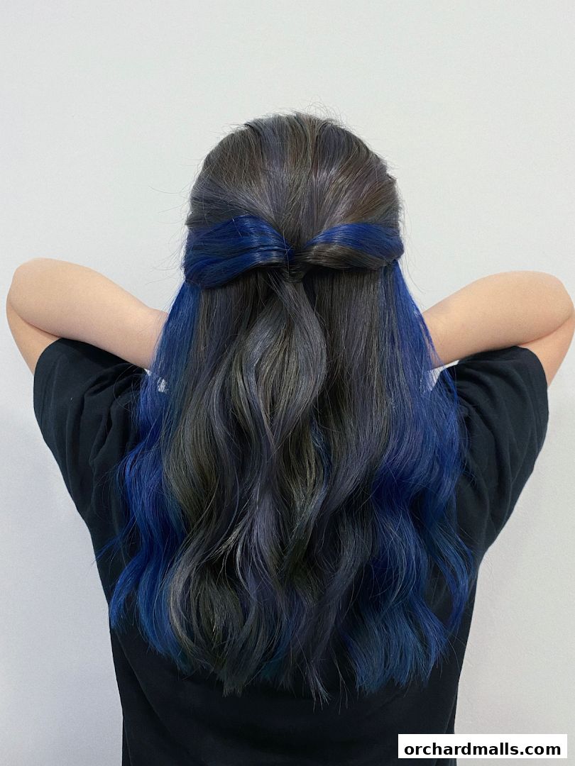 A person with dark hair styled with blue highlights and a bow tie shape.
