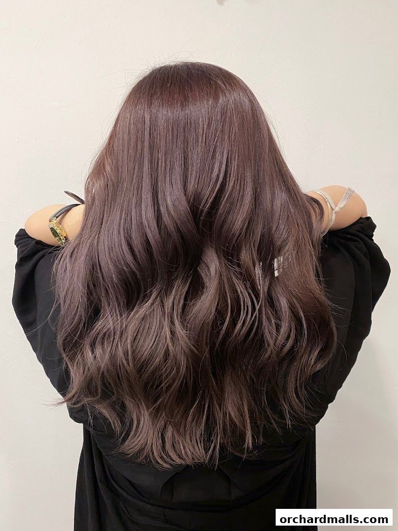 A person with long, wavy, ash-brown hair styled with a subtle ombre effect.