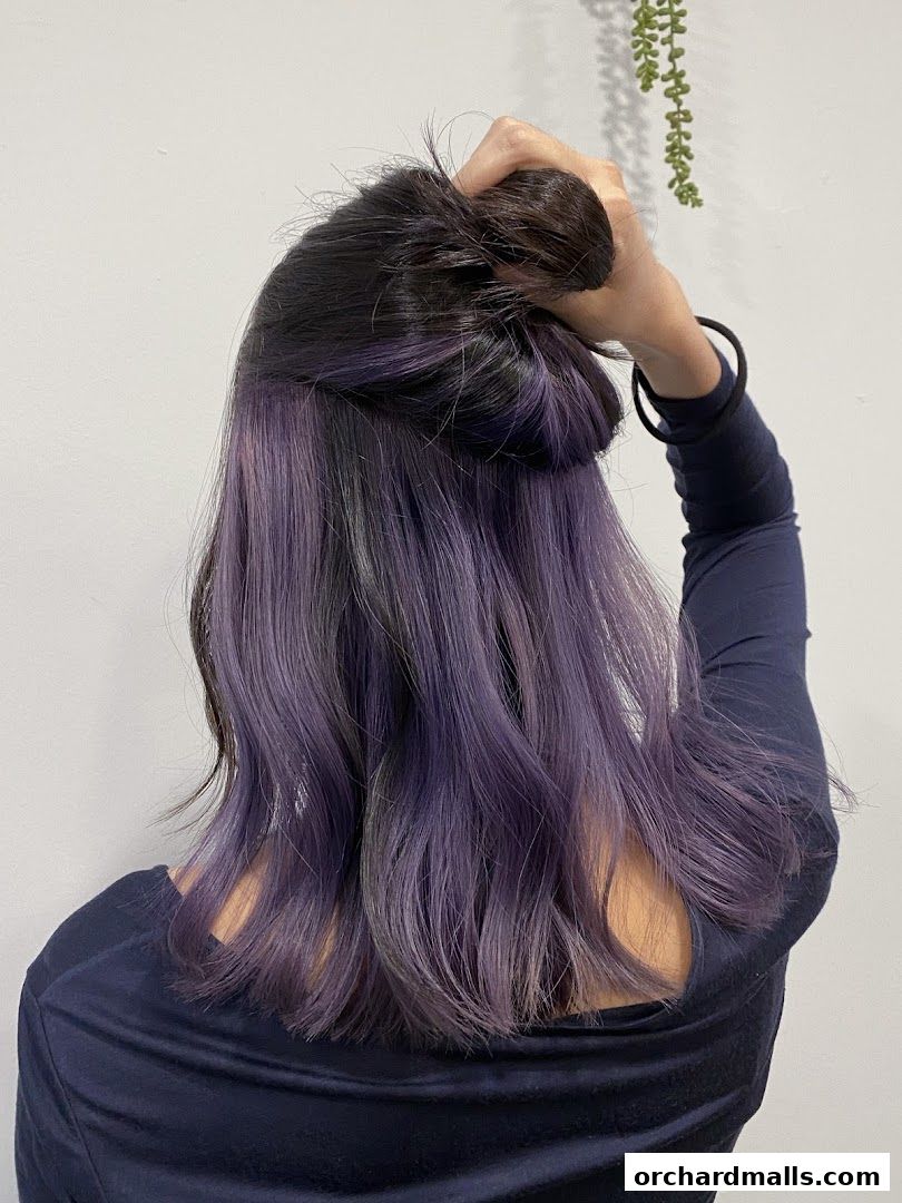 A person shows off their dark hair with stylish purple highlights.