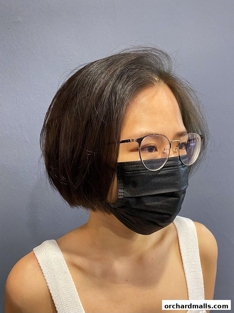 A person with a short bob haircut and glasses wearing a face mask.