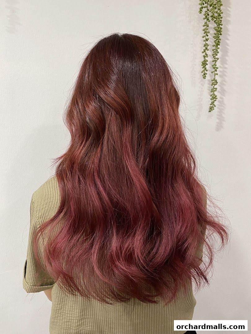 A person with long, wavy, burgundy and pink ombre hair.