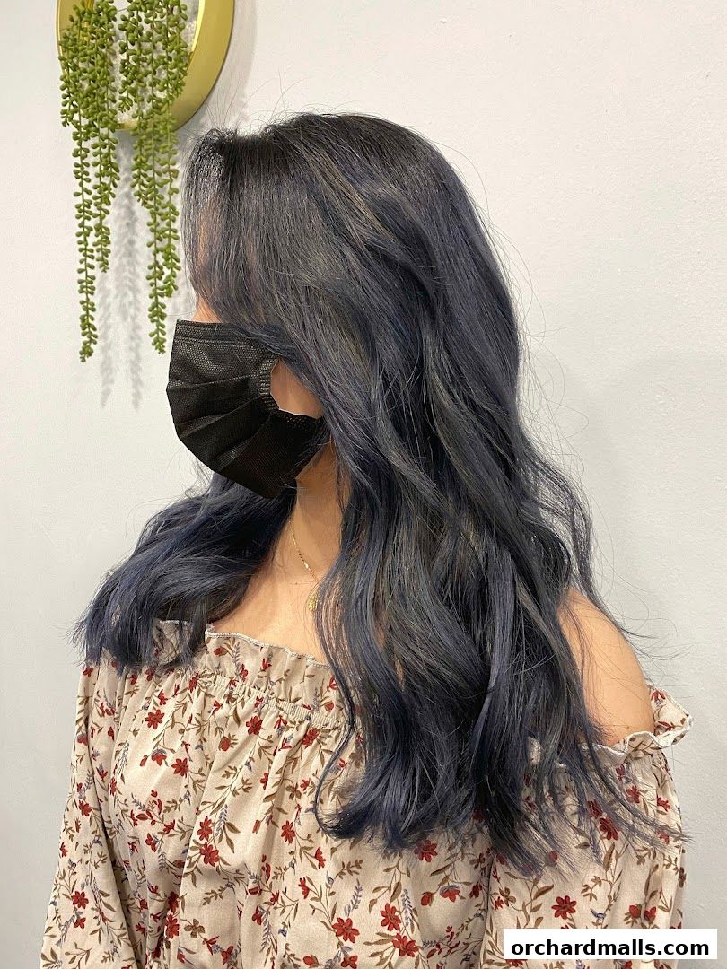 A person with stylish blue-grey wavy hair and a floral off-the-shoulder top.