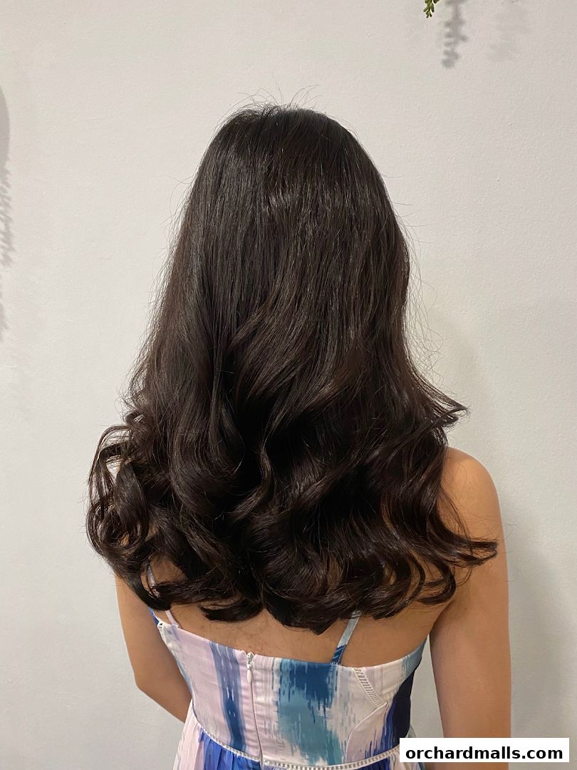 A woman's dark, wavy hair styled with volume and shine.