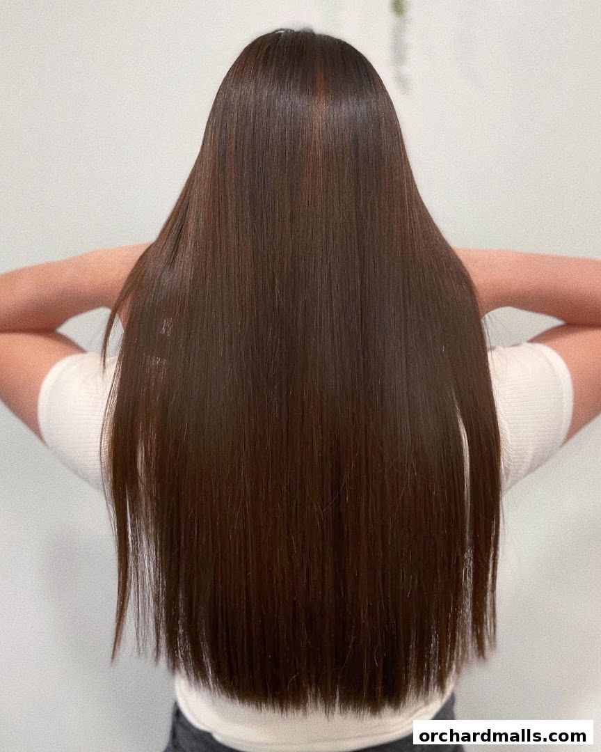 A person with long, straight, dark brown hair styled neatly.