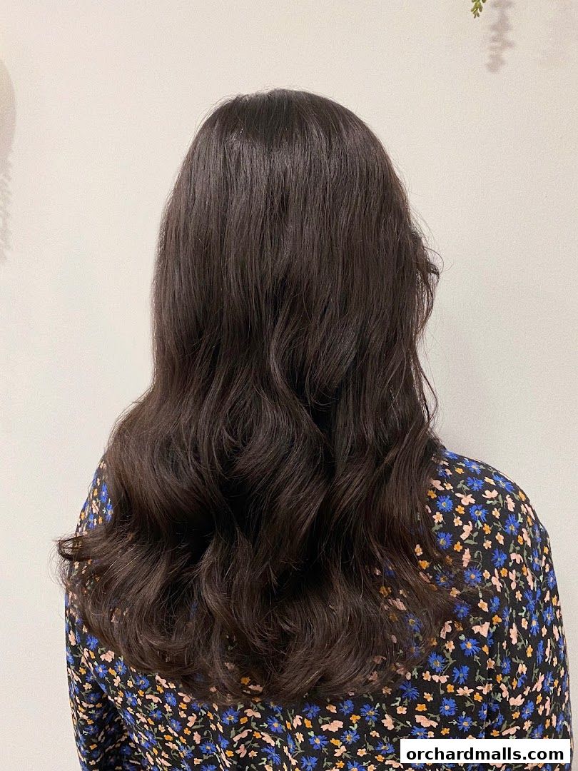 A person's back with long, wavy, dark brown hair styled beautifully.