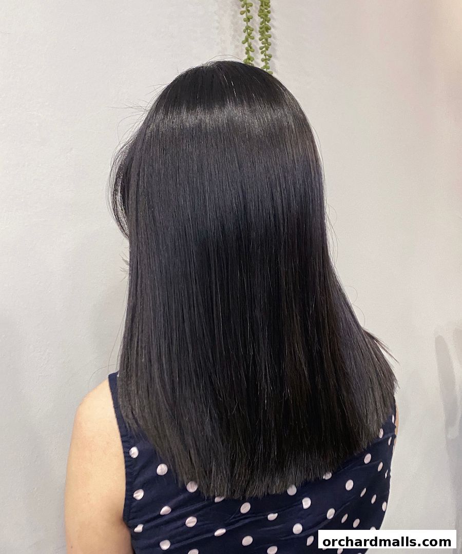 A person's back with long, straight, dark hair and a polka dot dress.