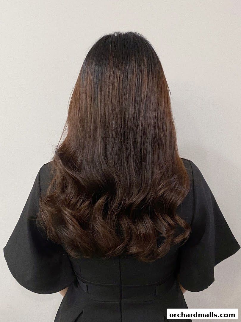 A person with long, dark, wavy hair styled with volume and shine.