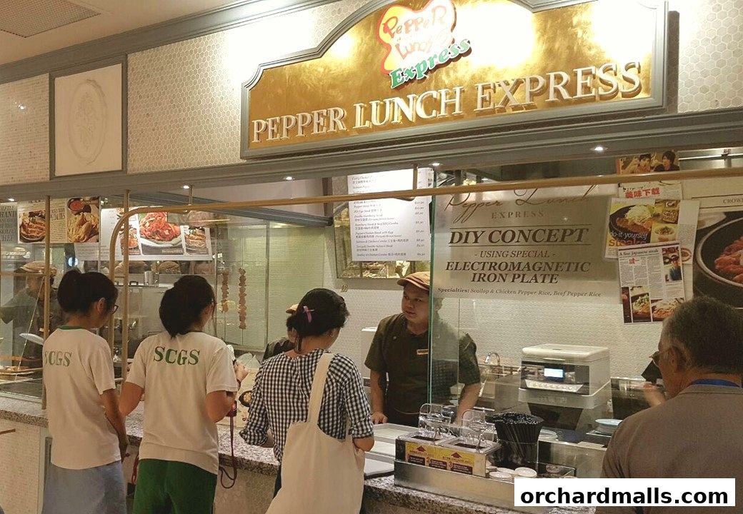 Customers ordering at Pepper Lunch Express with a staff member behind the counter.