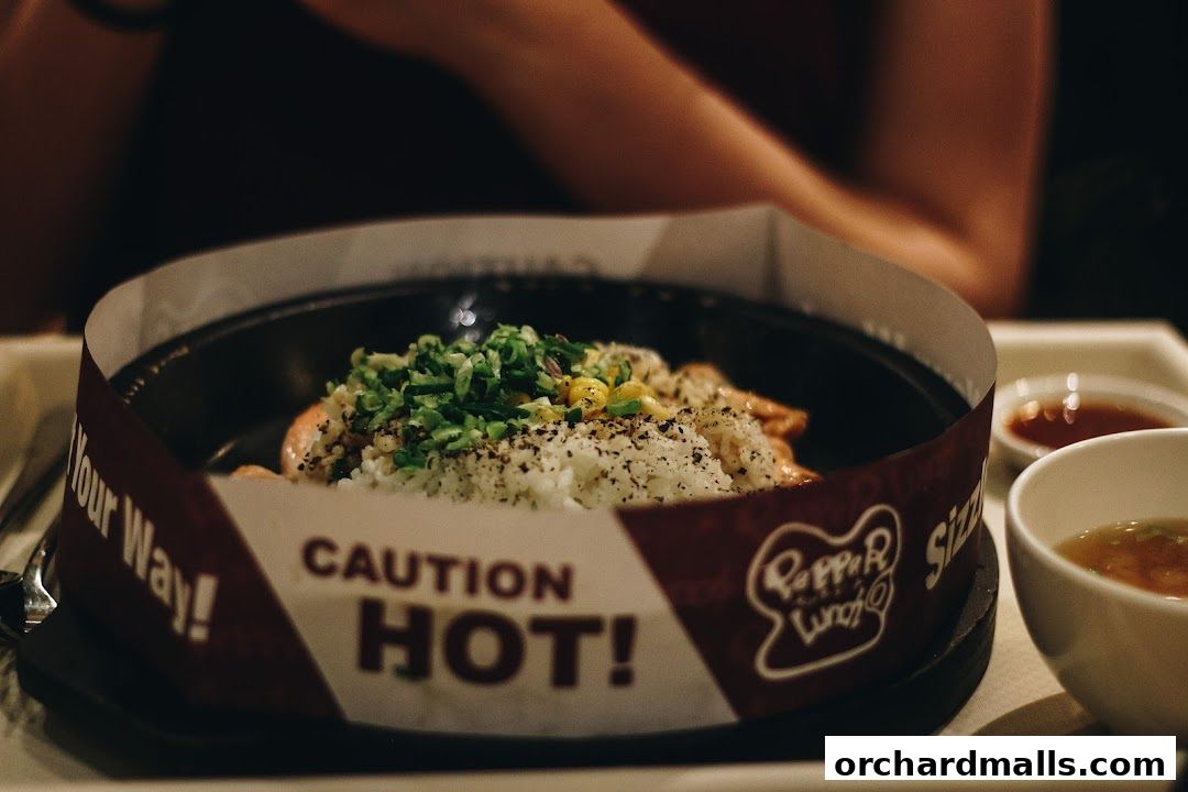 A close-up of a hot sizzling dish with rice, meat, and vegetables, served with soup.