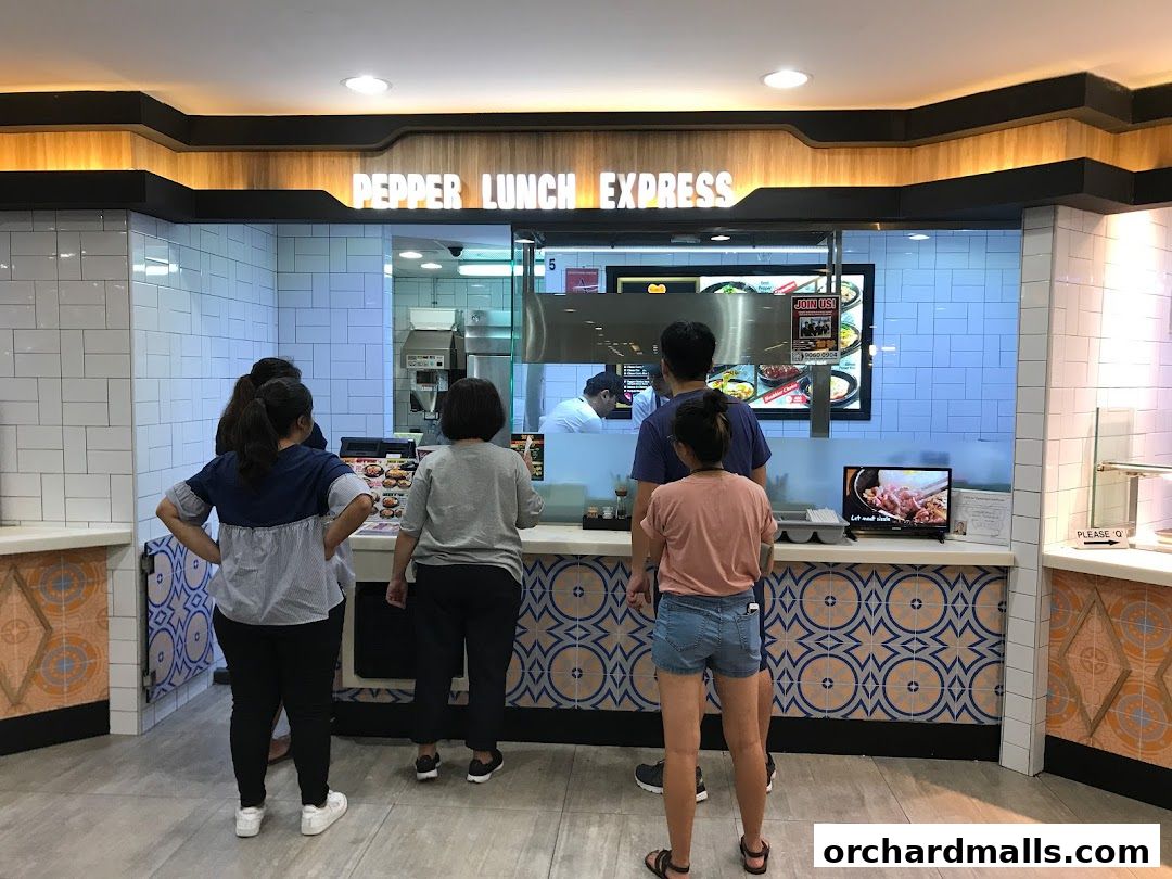 Customers queue at Pepper Lunch Express counter with menu displays and food visuals.