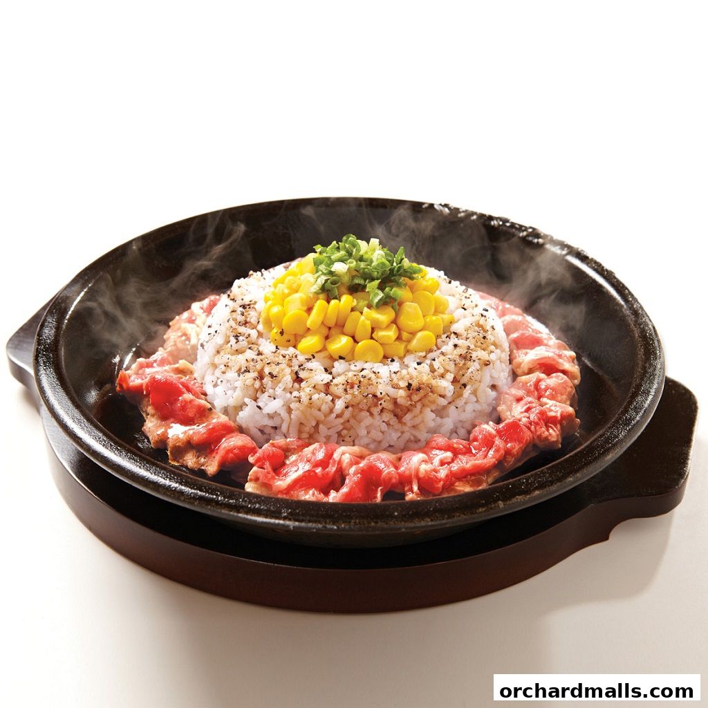 A sizzling hot plate of rice with beef and corn, garnished with spring onions.