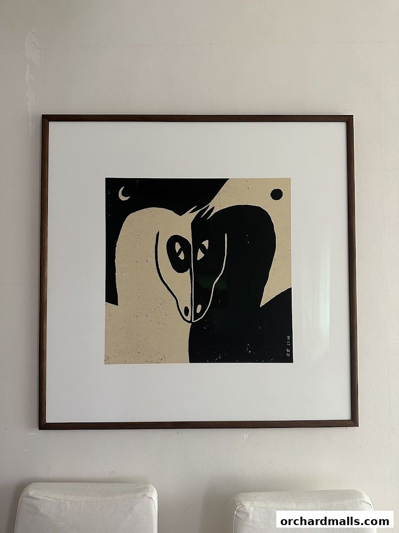 A framed artwork featuring two stylized horses in black and beige tones.
