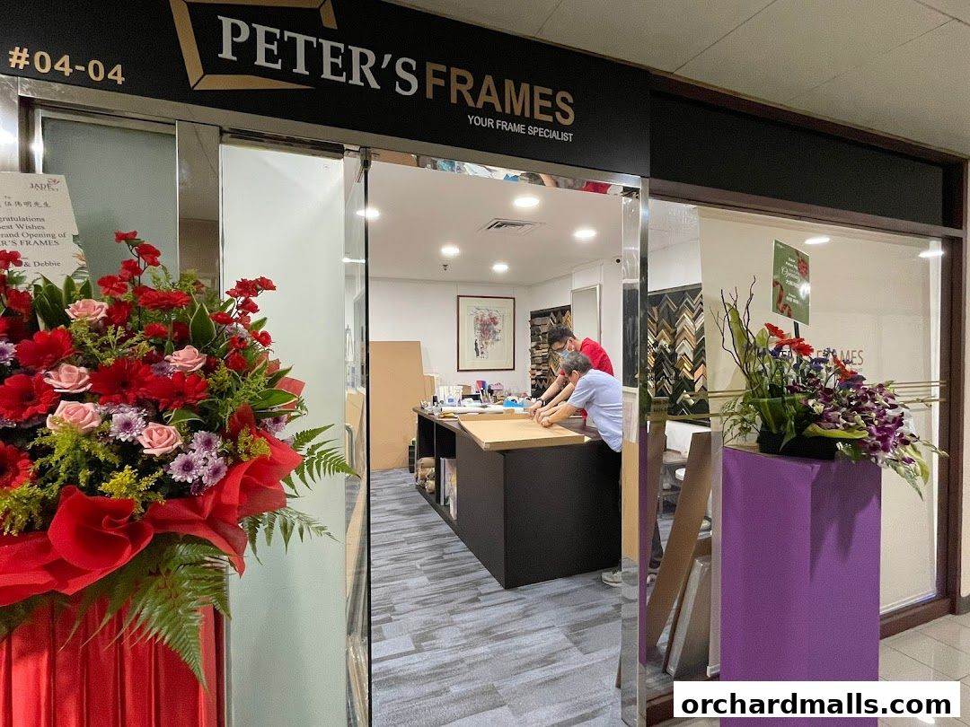 The exterior of Peter's Frames, a framing specialist shop, with floral arrangements and staff inside.