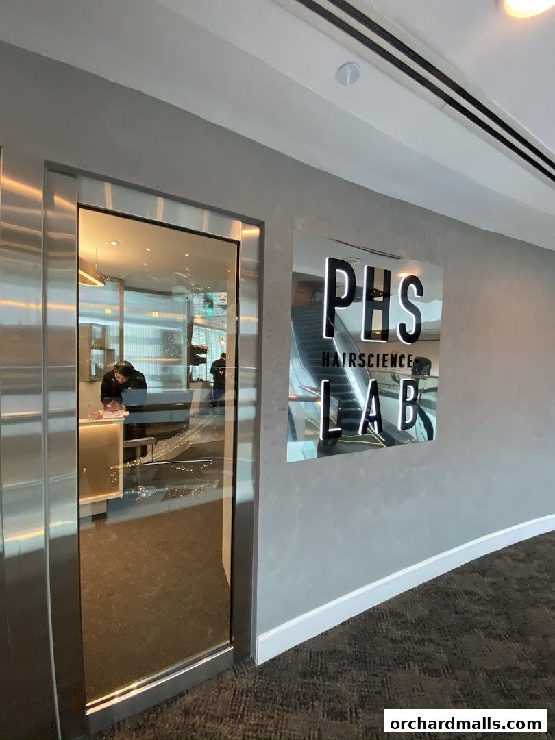 The entrance to PHS HAIRSCIENCE LAB at Wheelock Place, featuring a modern sign and glass door.