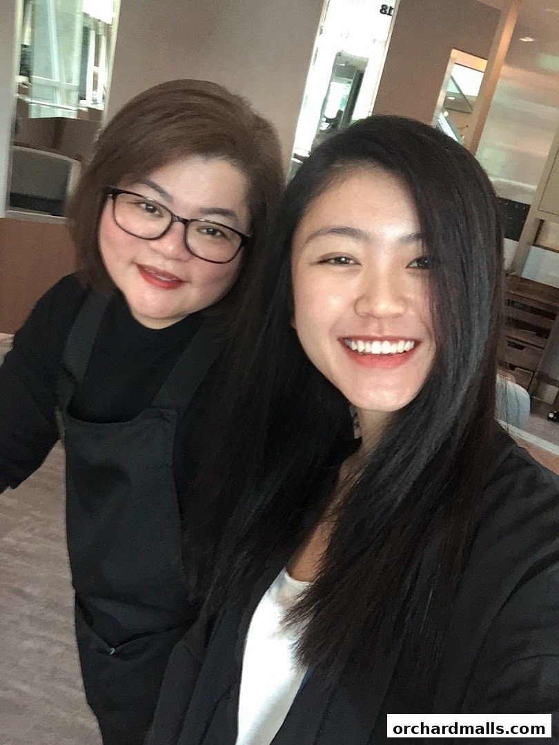 Two smiling women, likely staff, pose for a selfie inside a salon.