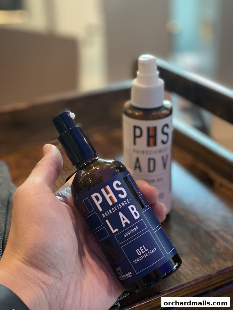 A hand holds a bottle of PHS HAIRSCIENCE LAB soothing gel for sensitive scalps.