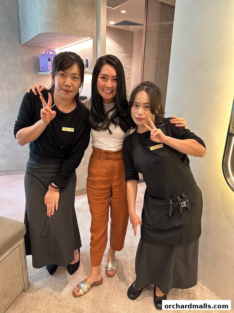 Three women posing for a photo inside a PHS HAIRSCIENCE LAB store.