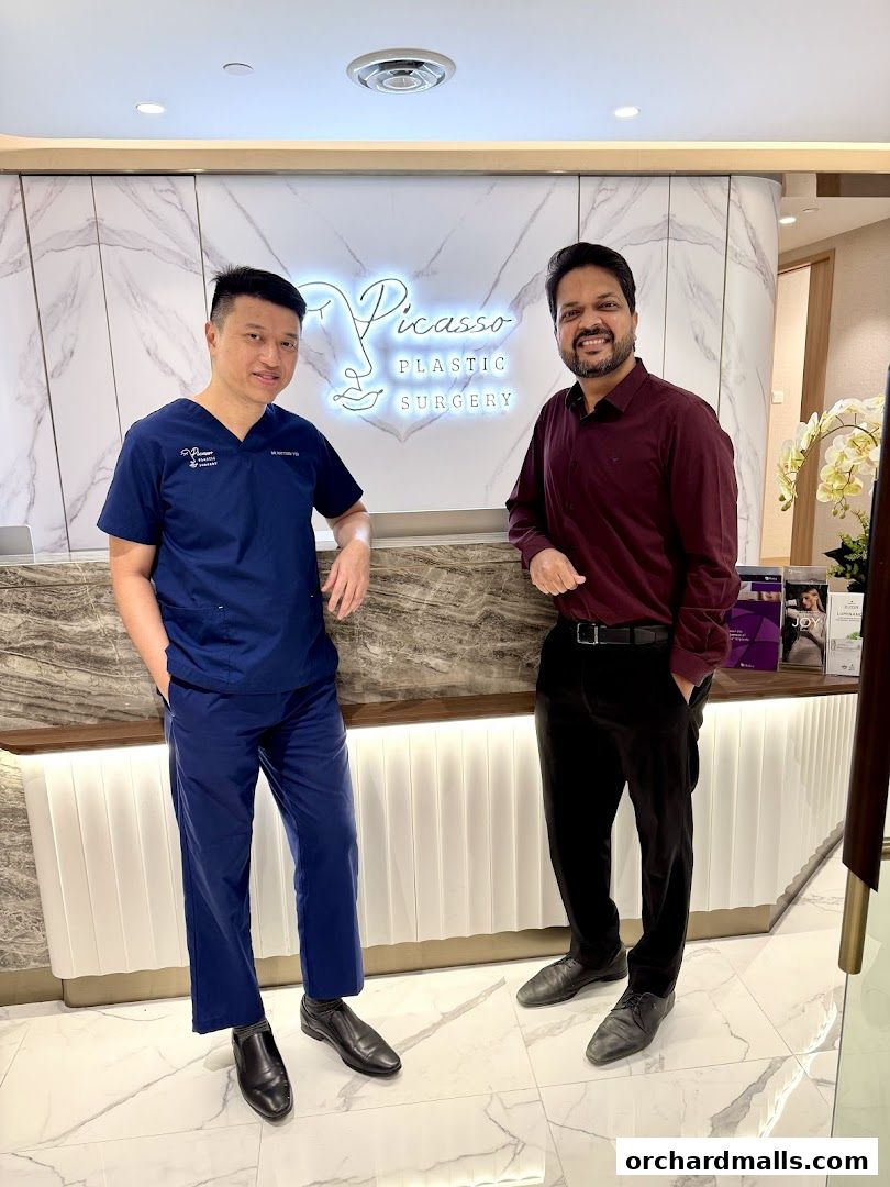 Two men stand in front of the Picasso Plastic Surgery reception area.