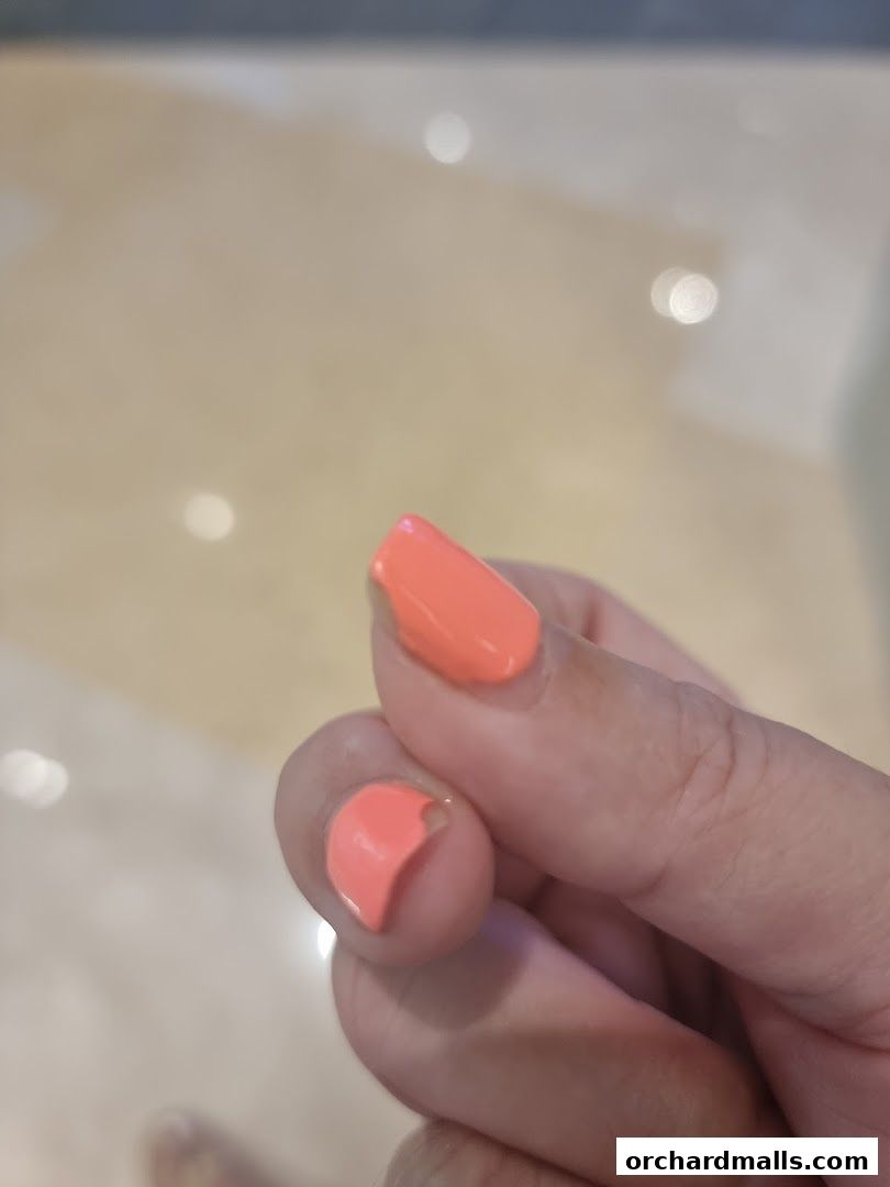 A close-up of a hand with chipped coral-colored nail polish.