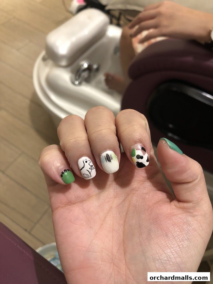 Close-up of a hand with creative nail art, including a cat and cow print design.