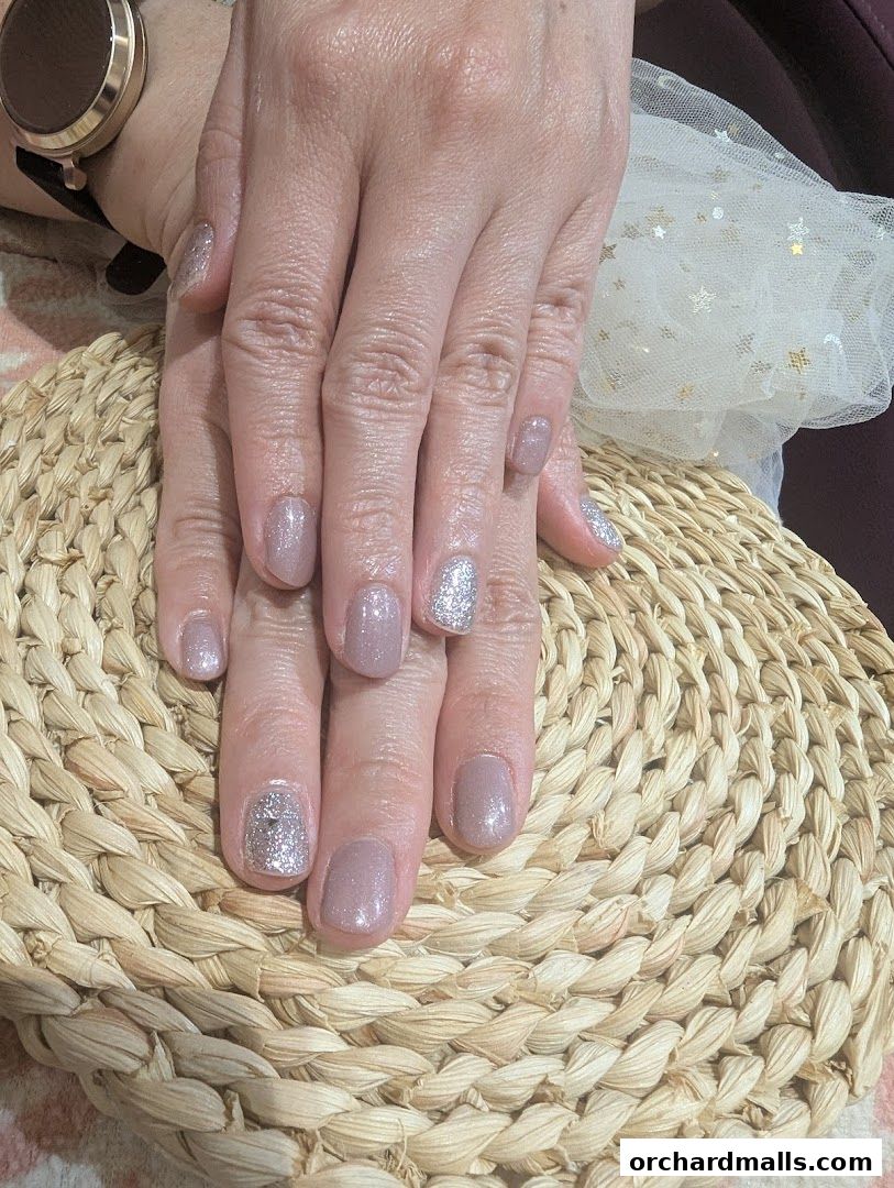 A close-up of hands with a subtle shimmer and glitter nail polish.