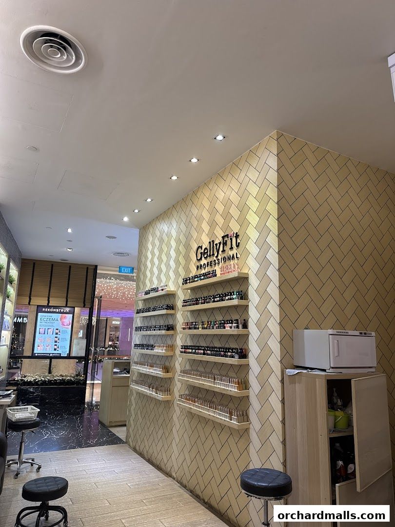 Interior view of a nail spa with shelves of nail polish and a display screen.