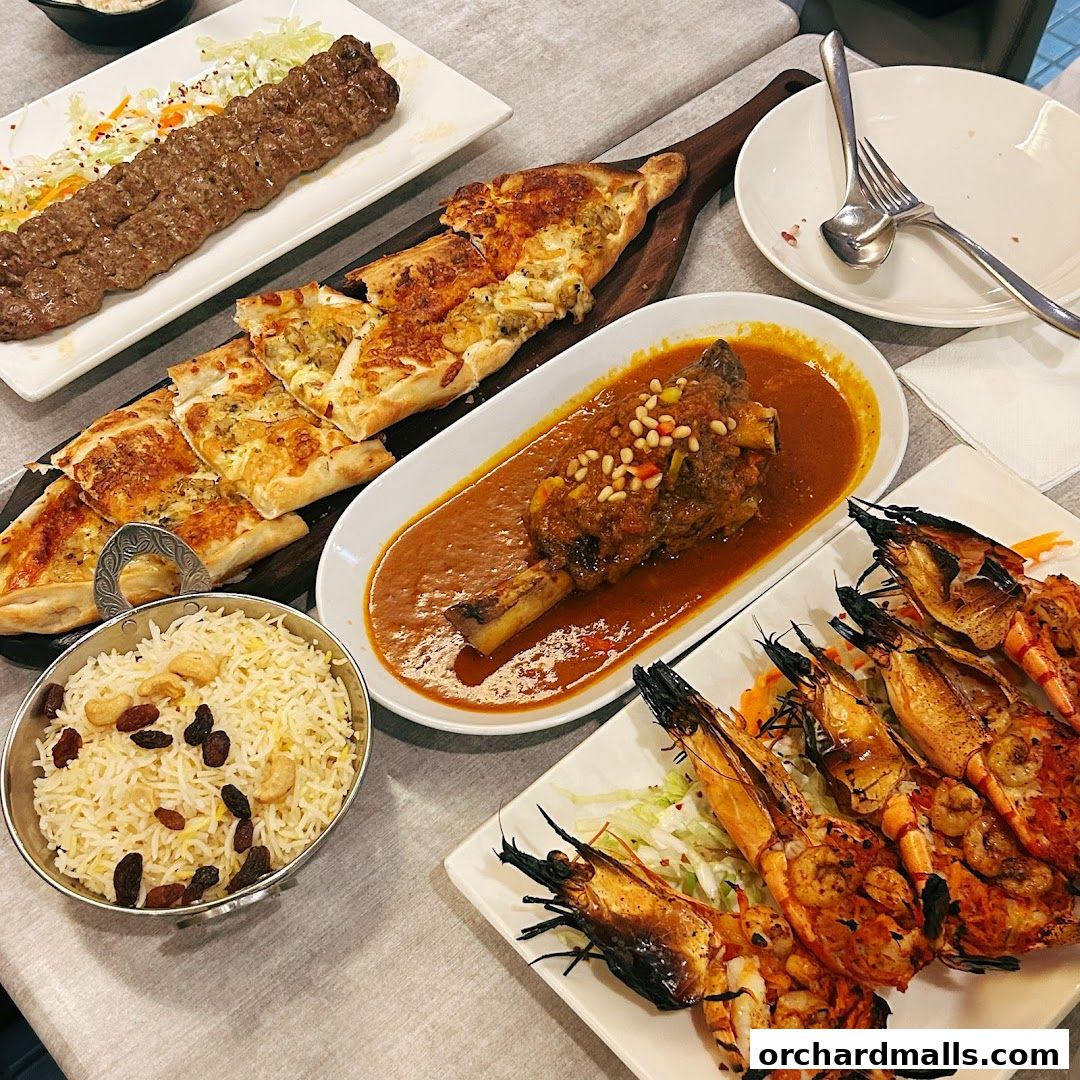 A spread of Middle Eastern and Mediterranean dishes including grilled shrimp, lamb shank, and flatbread.