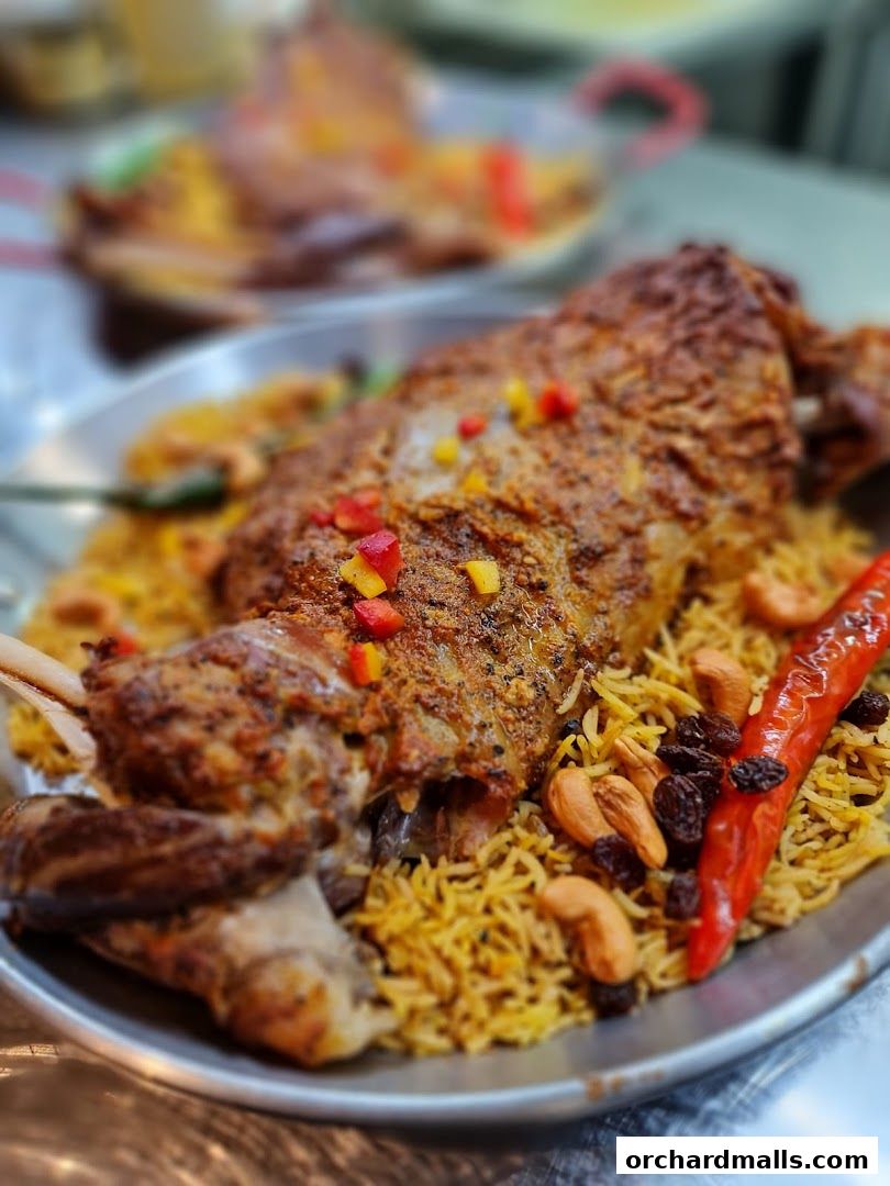 A platter of roasted lamb with rice, garnished with peppers, cashews, and raisins.