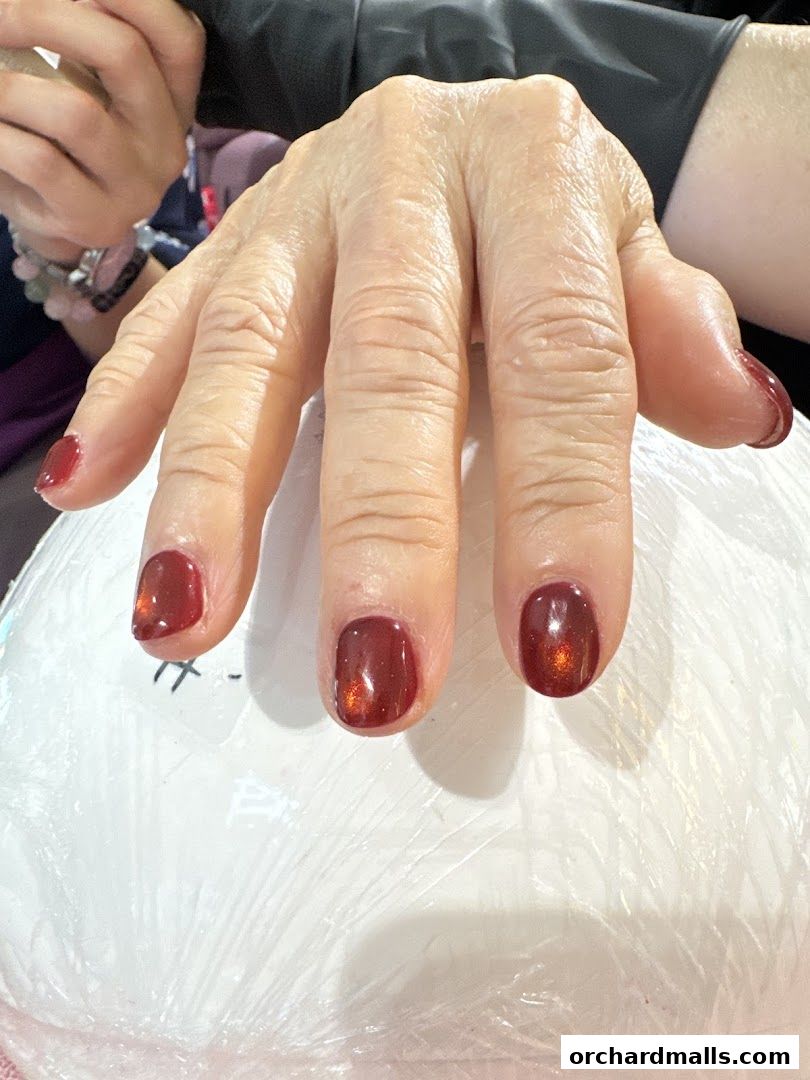 Close-up of a hand with freshly painted dark red nails.