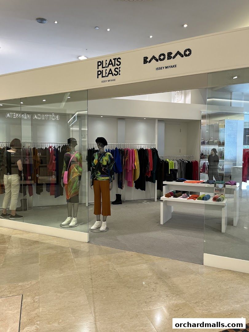 The storefront of PLEATS PLEASE ISSEY MIYAKE, showcasing colorful pleated garments and accessories.