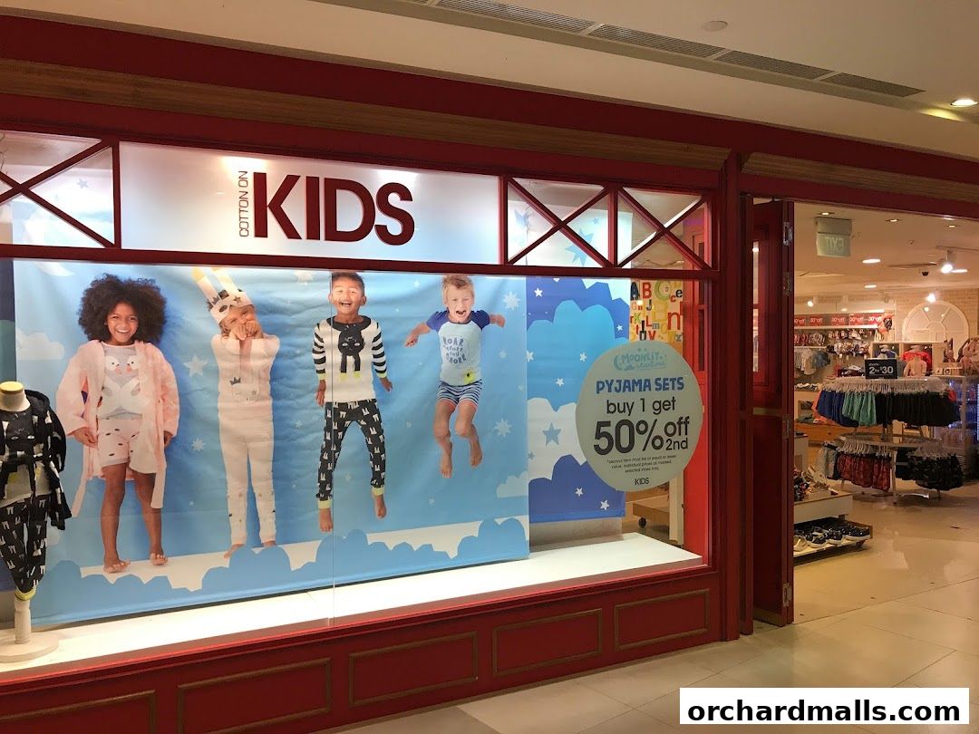 Cotton On Kids store window display featuring children in pajamas and a promotional offer.