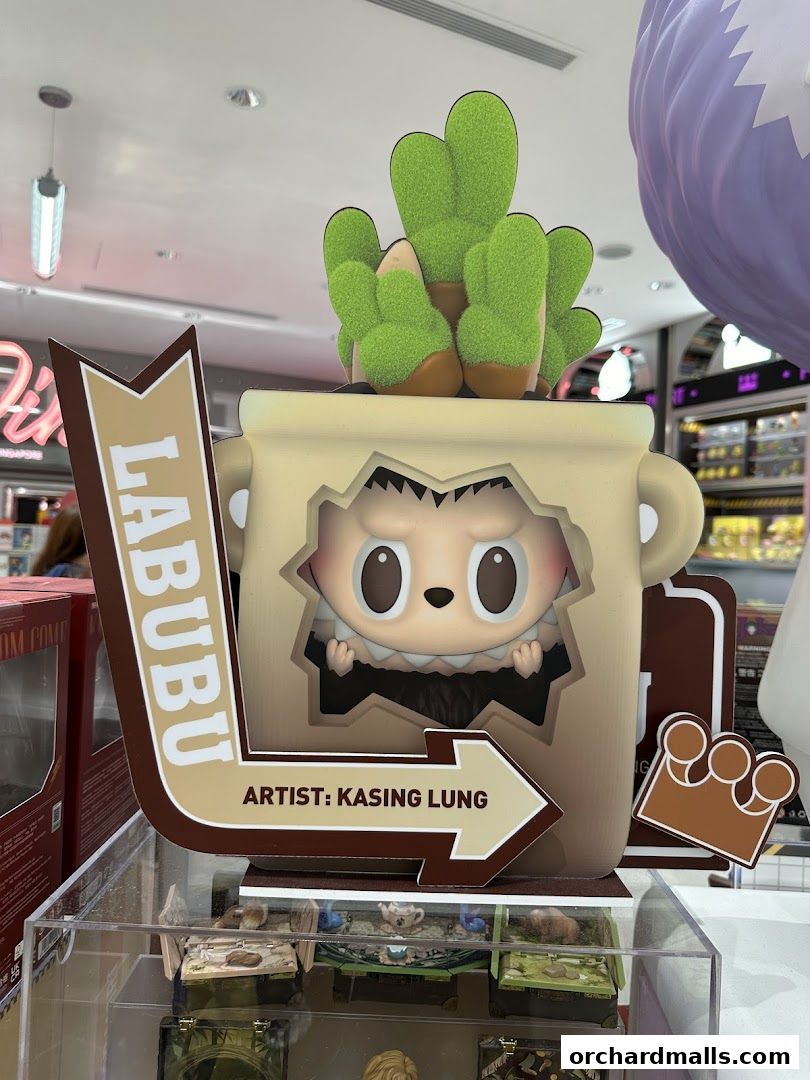 A POP MART display featuring a Labubu figurine in a pot with cacti, signed by artist Kasing Lung.