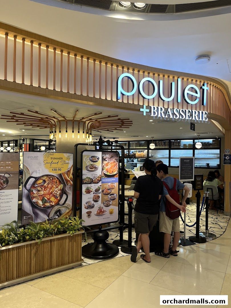 The entrance of Poulet + Brasserie with a menu display and customers waiting.
