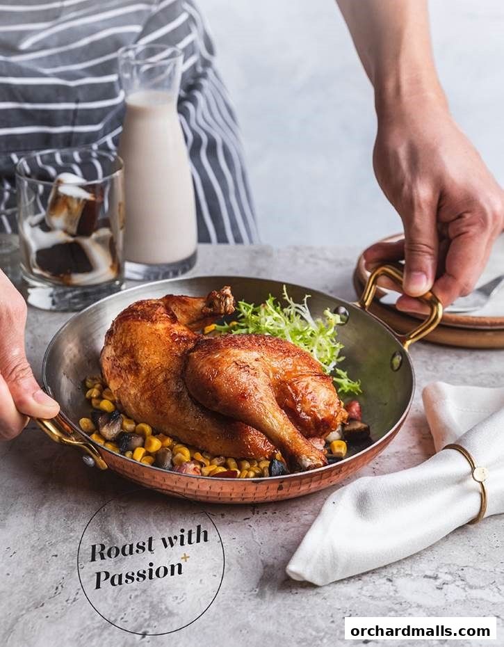 A person serves a roasted chicken dish with corn and salad, accompanied by a drink.