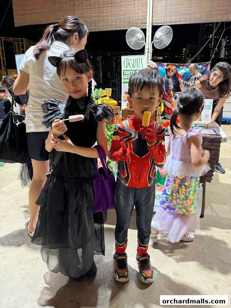 Children in costumes enjoy treats at a festive outdoor event.