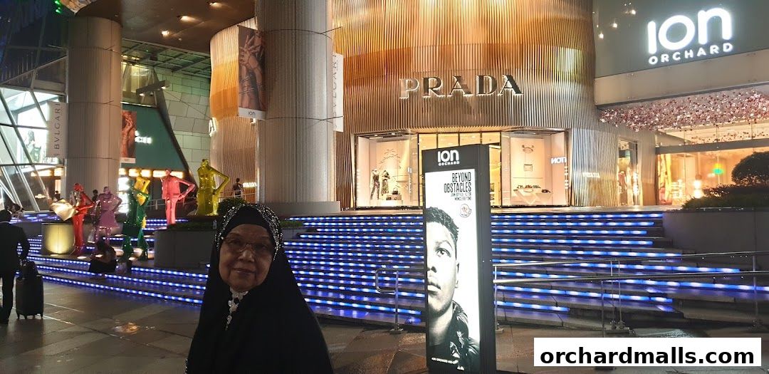 A woman poses in front of the illuminated Prada store entrance at ION Orchard.