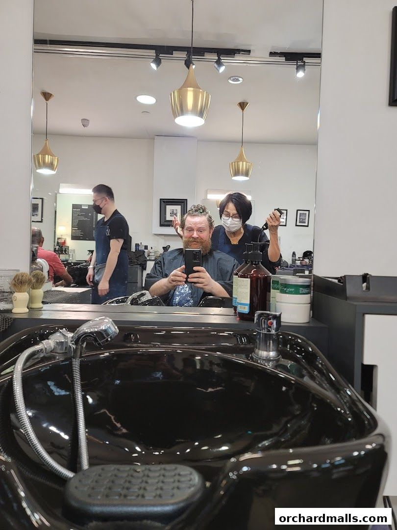 A barber is cutting a customer's hair in a modern barbershop with stylish lighting.