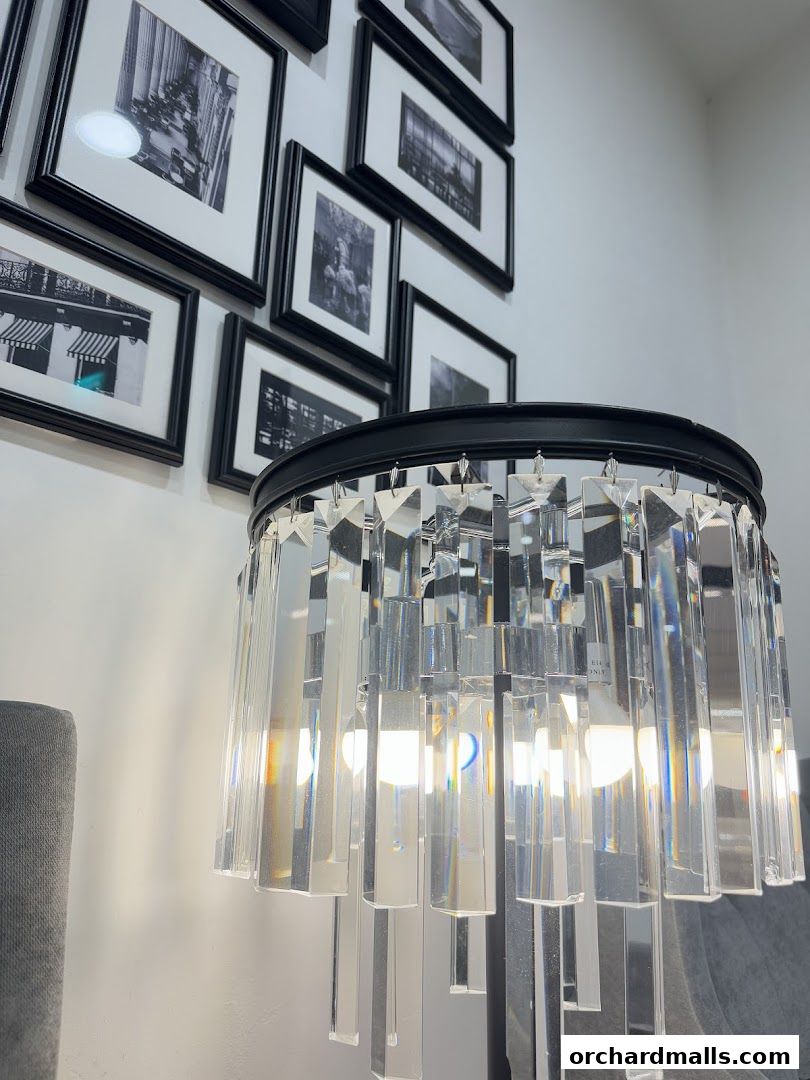 A crystal chandelier hangs in front of a wall adorned with framed black and white photographs.