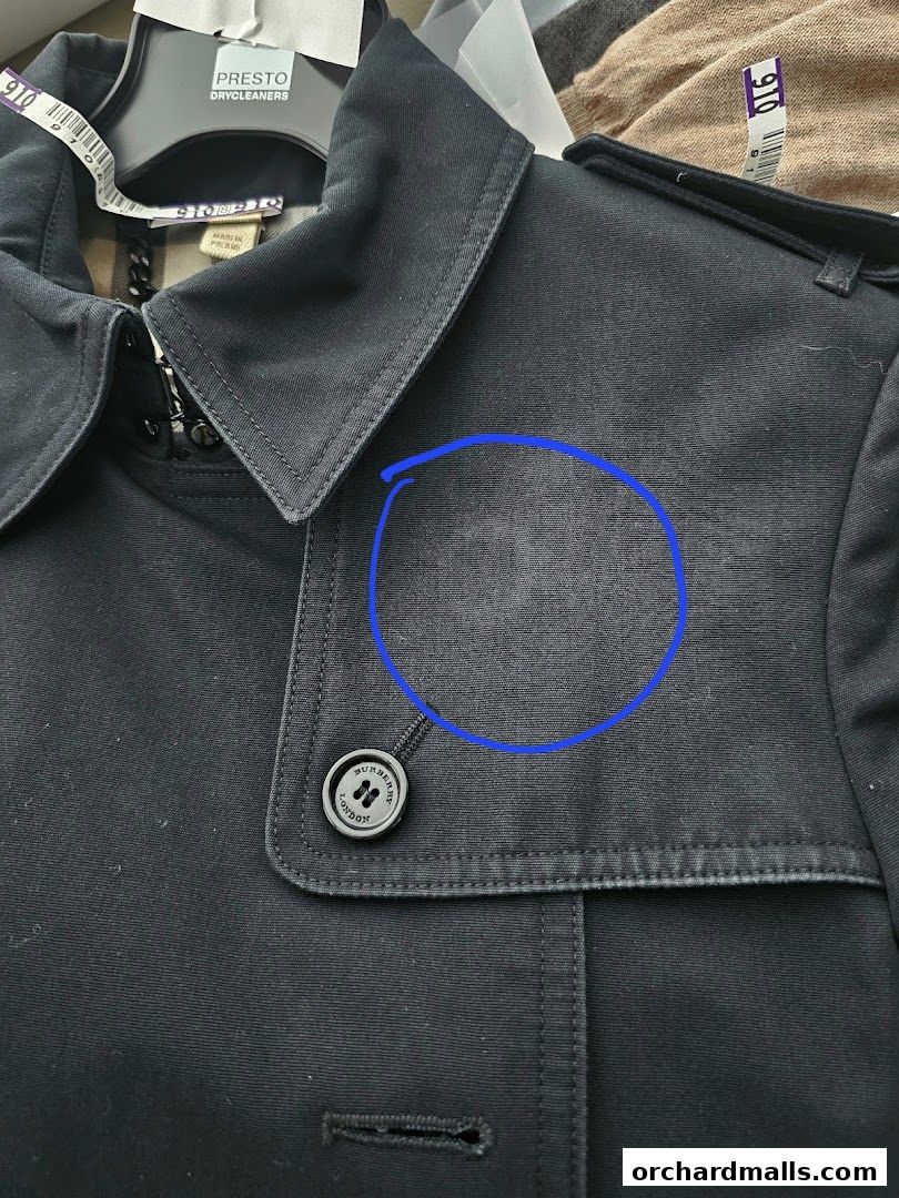 Close-up of a black Burberry jacket with a stain circled on the fabric.